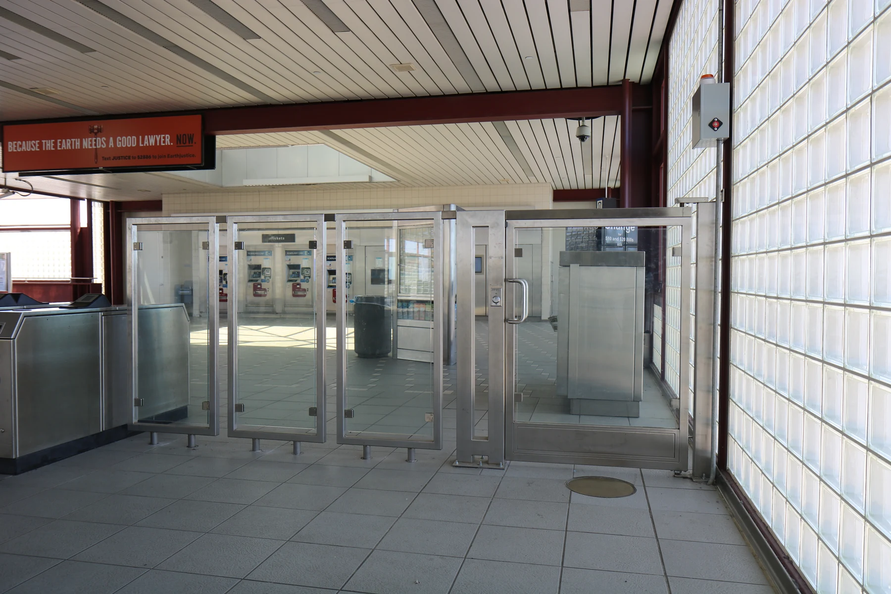 Tall clear-panel gate and adjoining barrier panels beside station equipment